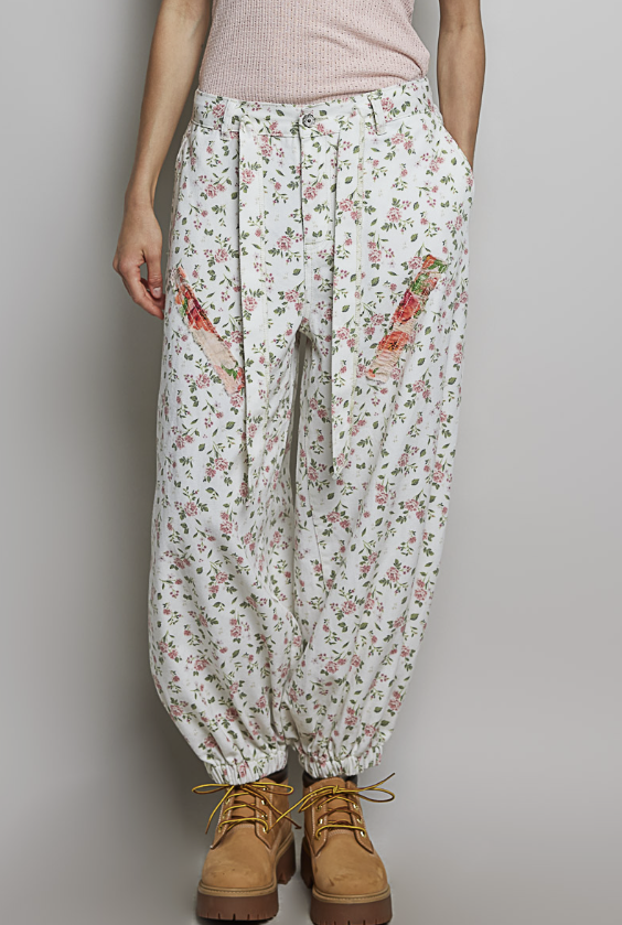 Woman wearing floral balloon pants on plain background