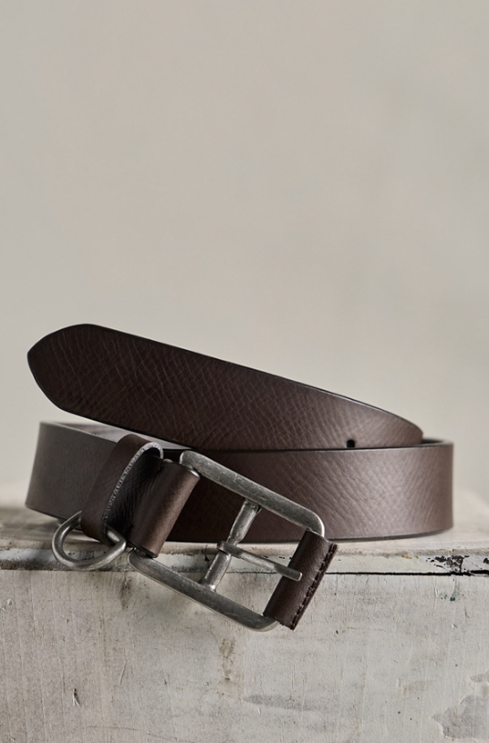 Brown belt with brushed silver details on concrete slab