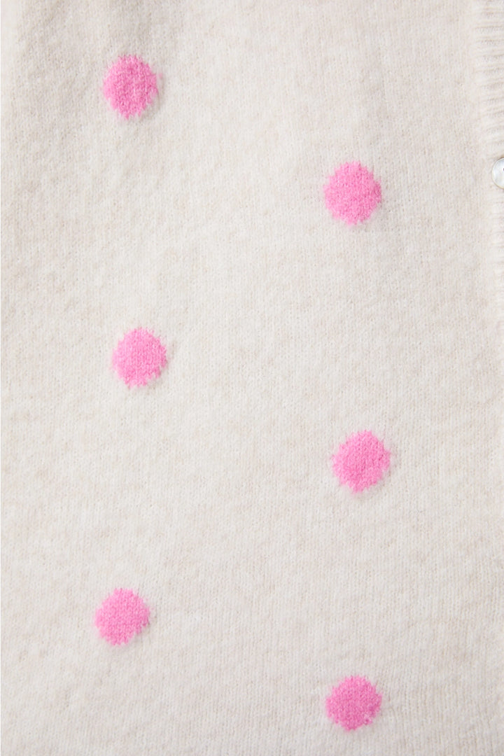 Close-up of a textured fabric with pink pom-poms on a light background