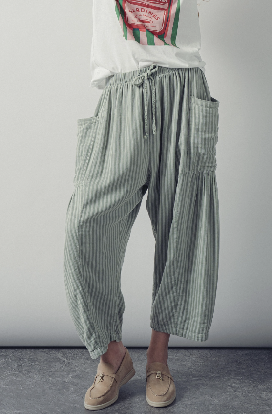 Person wearing green striped pants and a white shirt with red text against a plain background