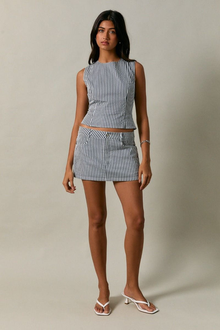 Woman wearing a navy and white striped outfit on a plain background