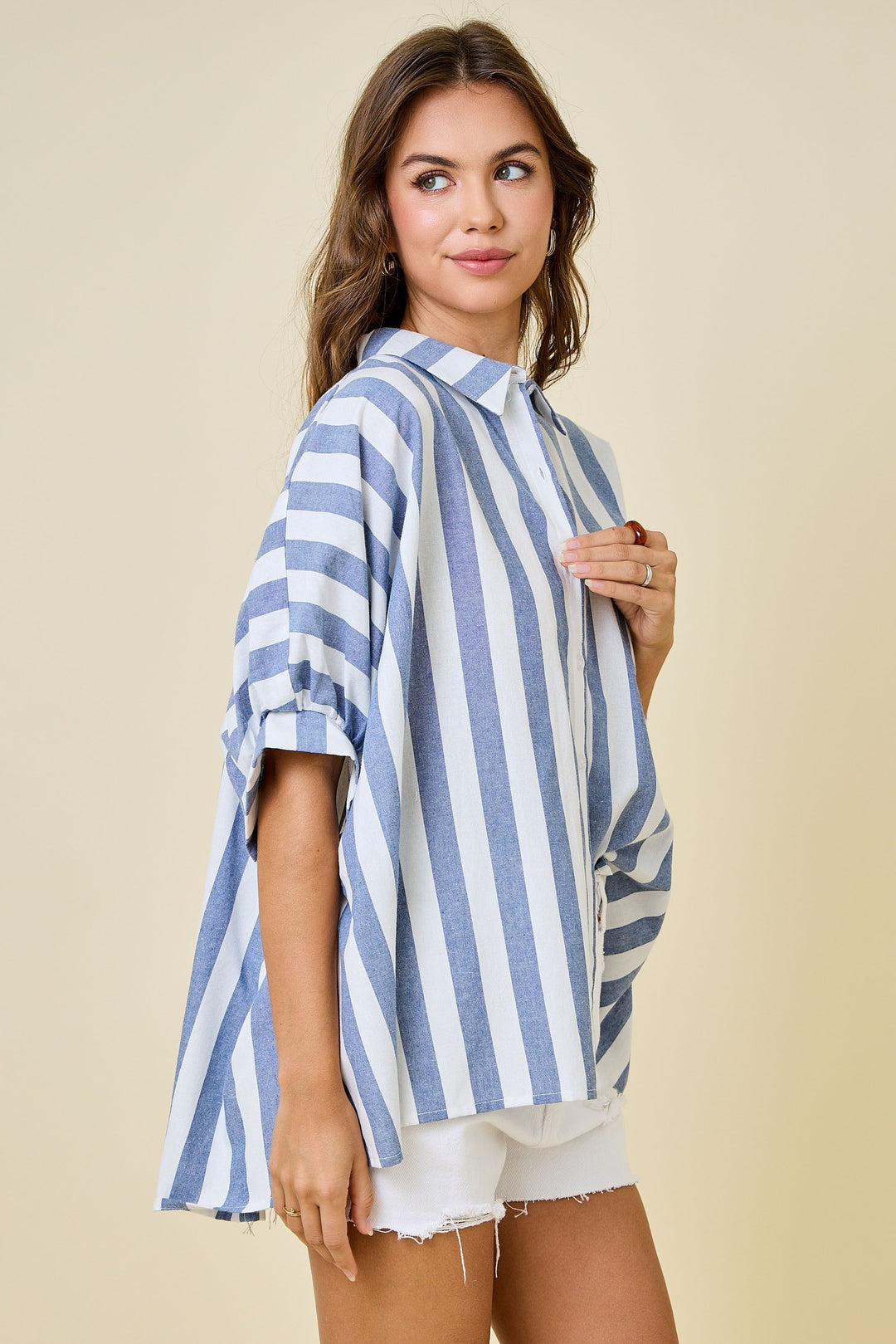Woman wearing a blue and white striped shirt against a beige background