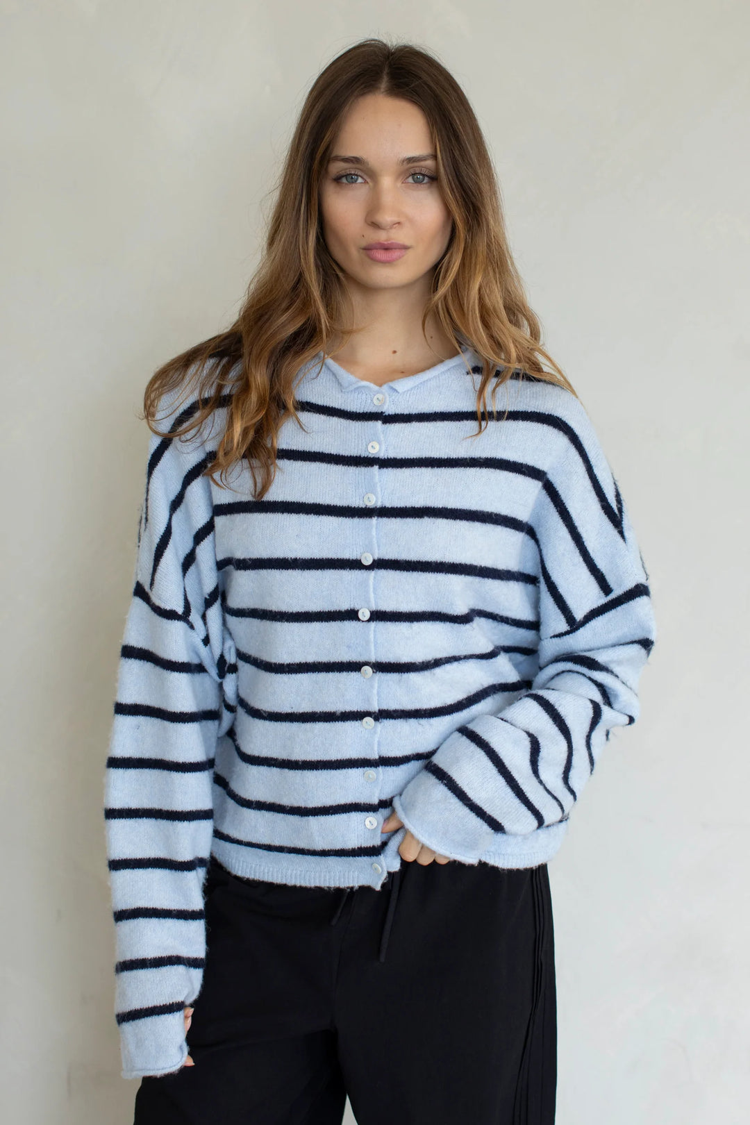 Woman wearing blue striped cardigan on plain background