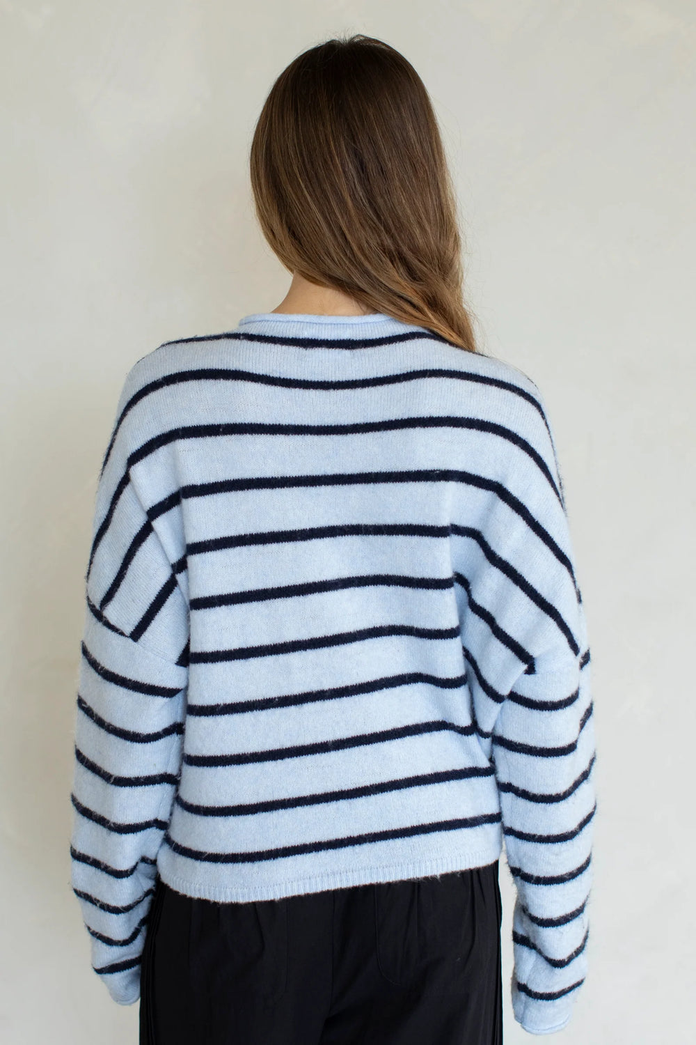 Person wearing a blue and white striped sweater against a plain background