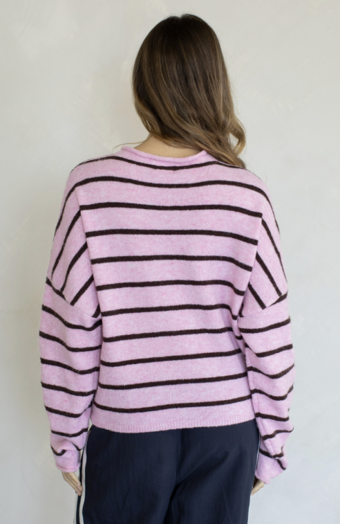 Woman shown from behind wearing pink and brown stripe cardigan on plain background