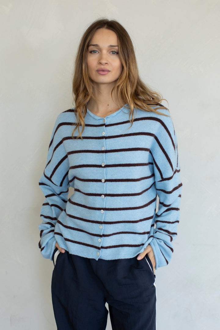 Woman wearing blue and brown stripe cardigan on plain background