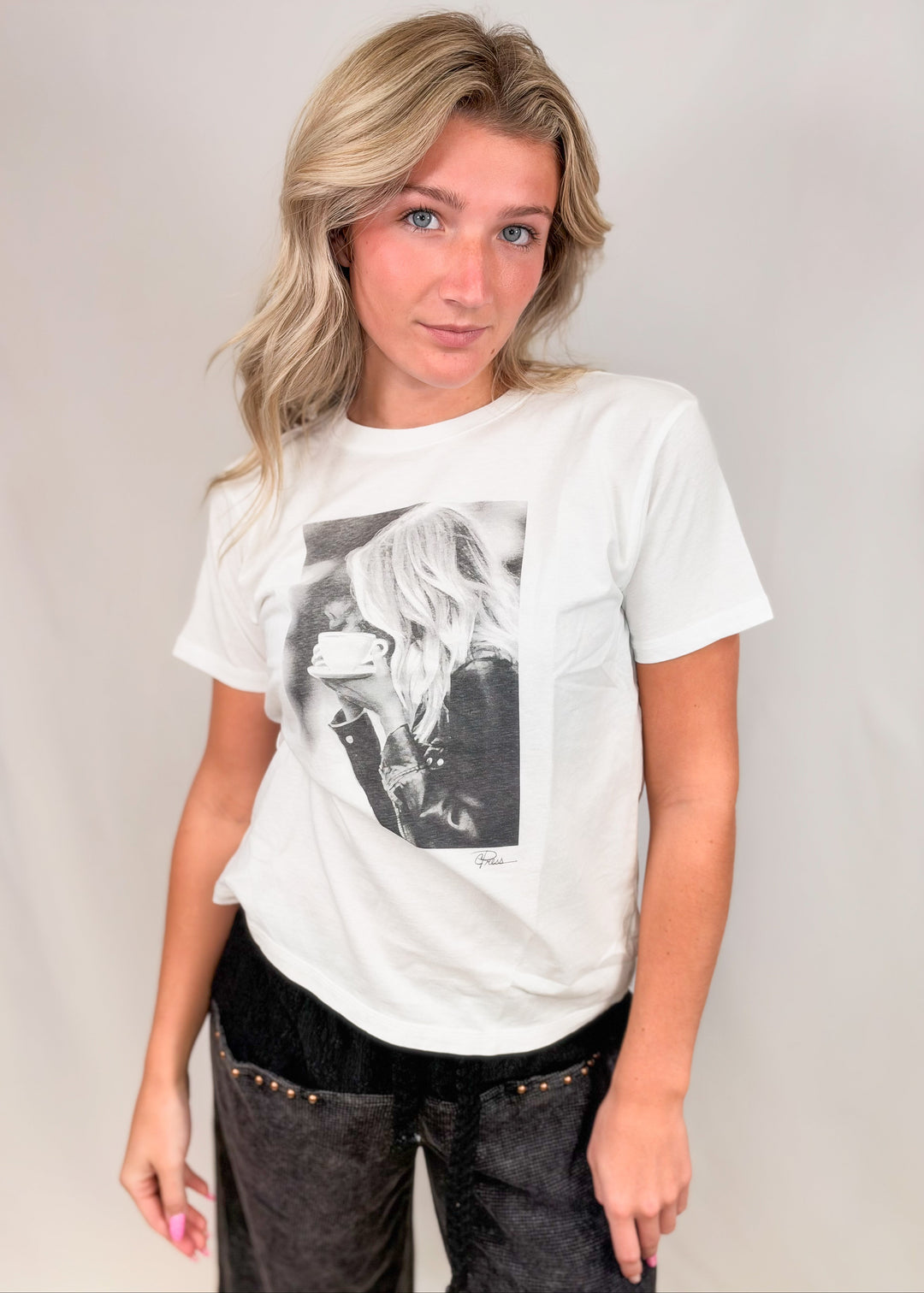 Woman wearing graphic tee of woman drinking coffee on plain background