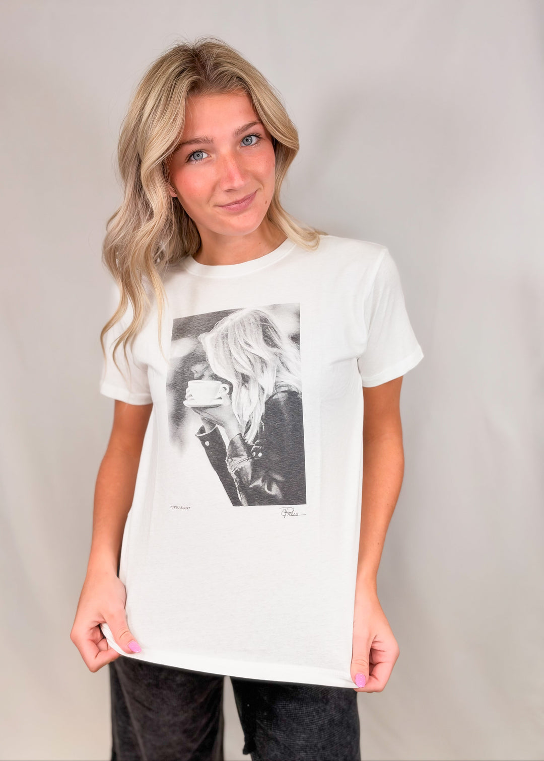 Woman wearing graphic tee of woman drinking coffee on plain background