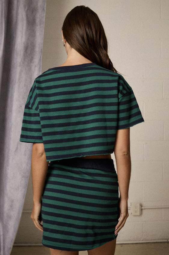 Woman shown from behind wearing green and blue stripe set in studio setting