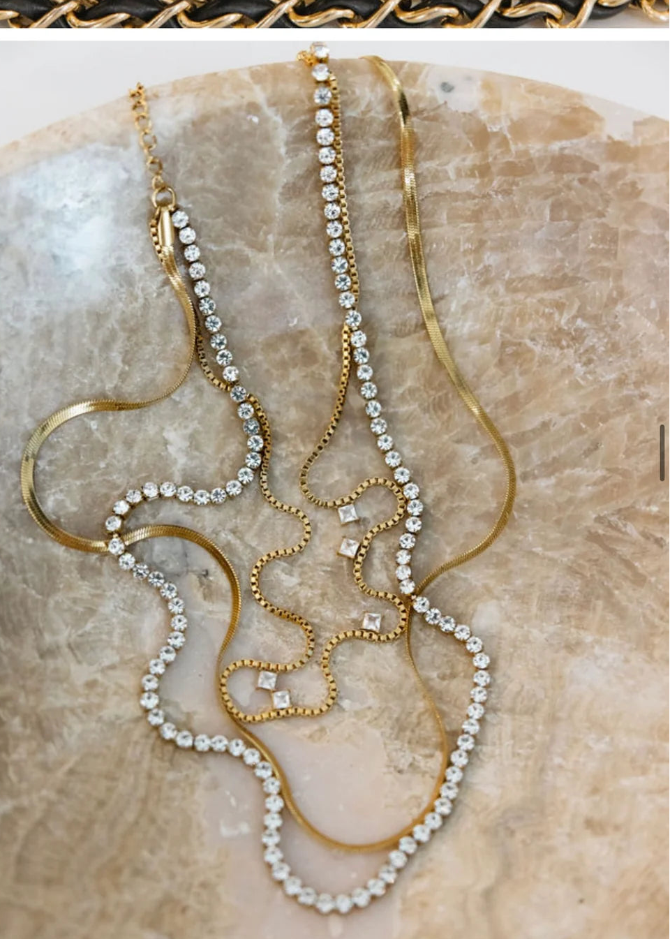 Triple layered gold and diamond necklace on marble slab