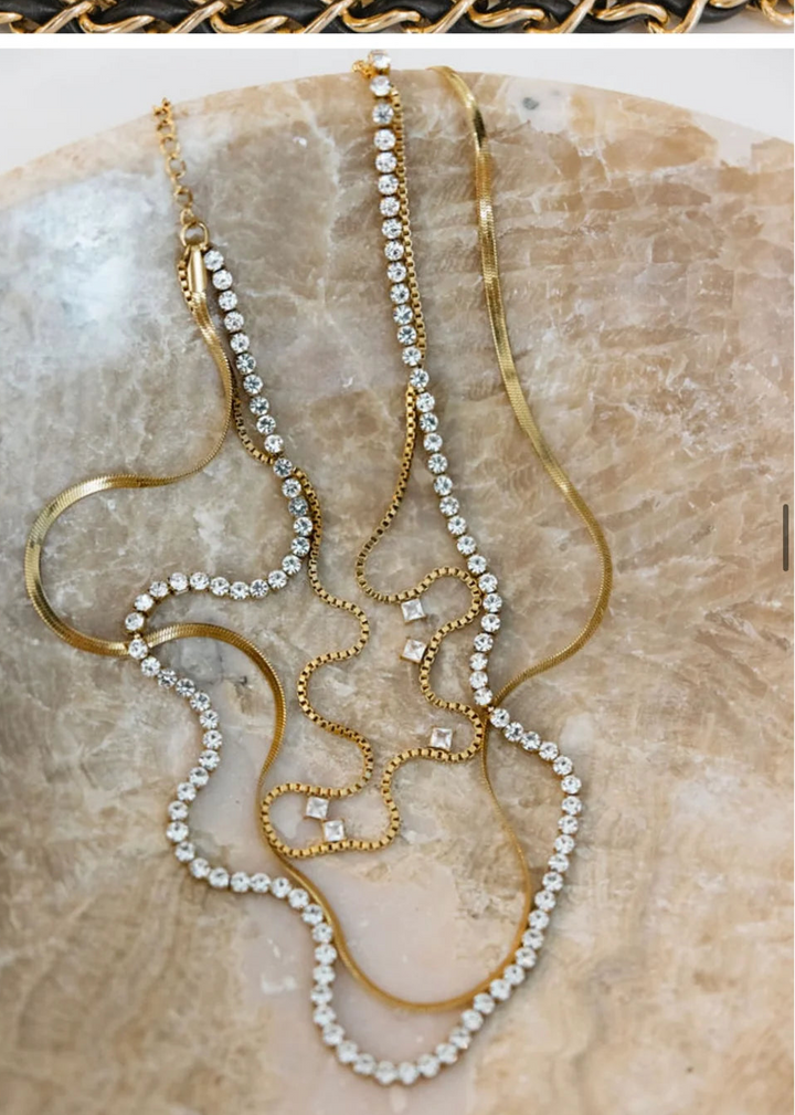 Triple layered gold and diamond necklace on marble slab