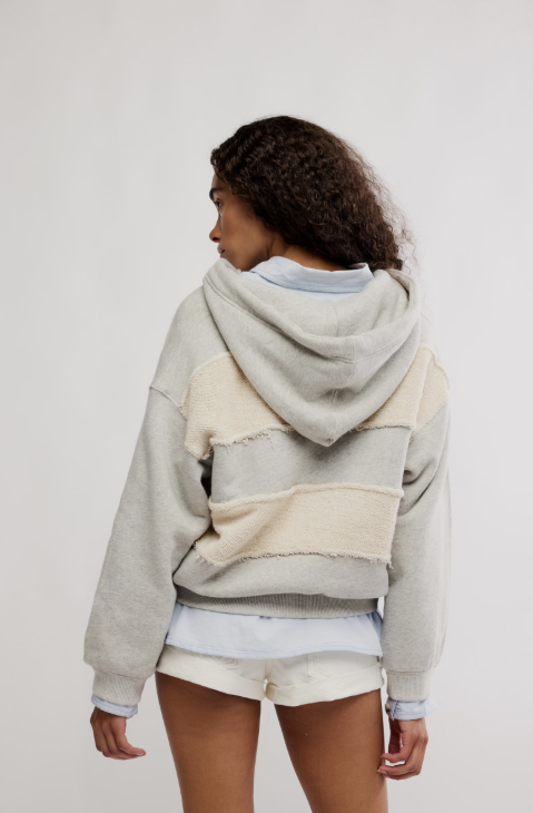 Person wearing a gray and beige striped hoodie on a white background