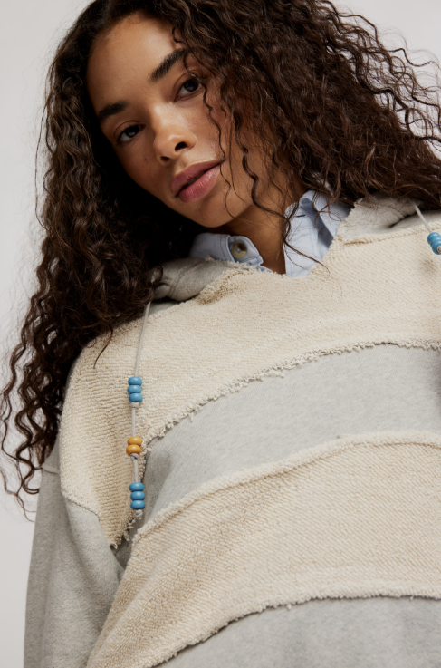 Woman wearing a beige and gray striped sweater with colorful beads.