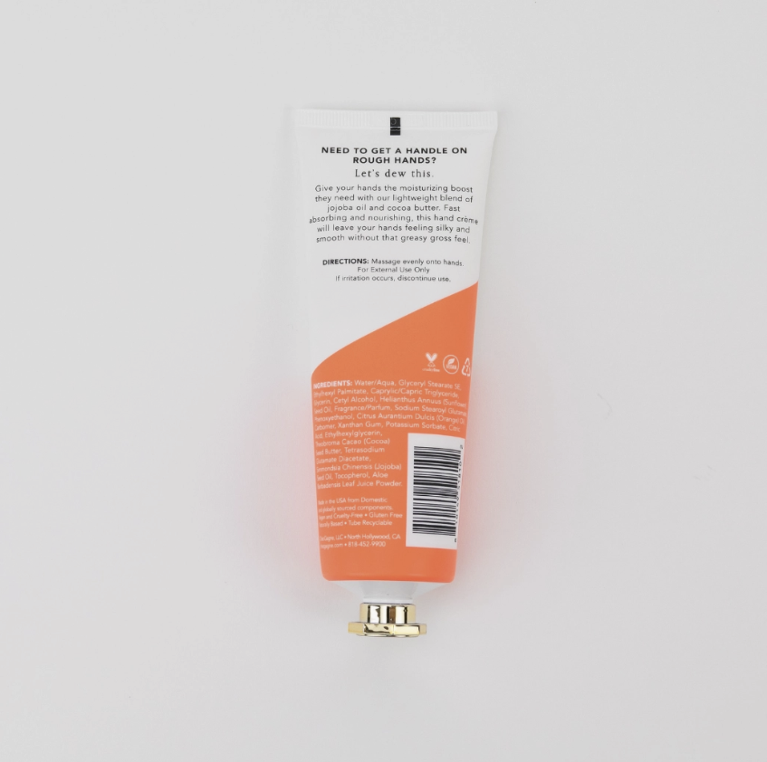 A squeeze tube of hand cream shown from the back, featuring white and orange packaging with text instructions, alongside a small gold metal cap on a clean white background.