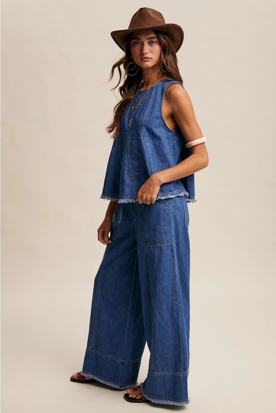Woman wearing a denim outfit with a brown hat on a beige background