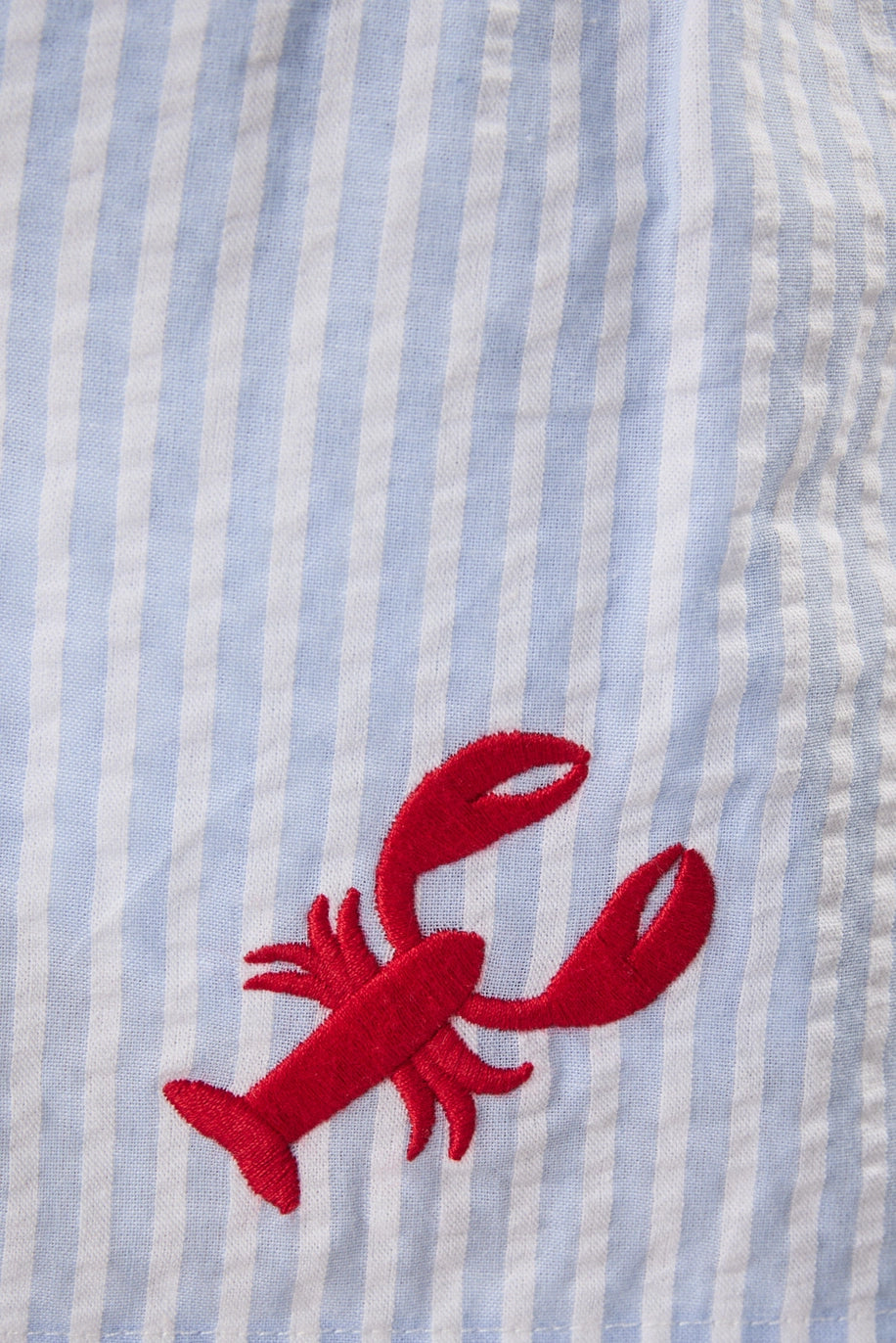 Red lobster embroidery on a blue and white striped fabric background