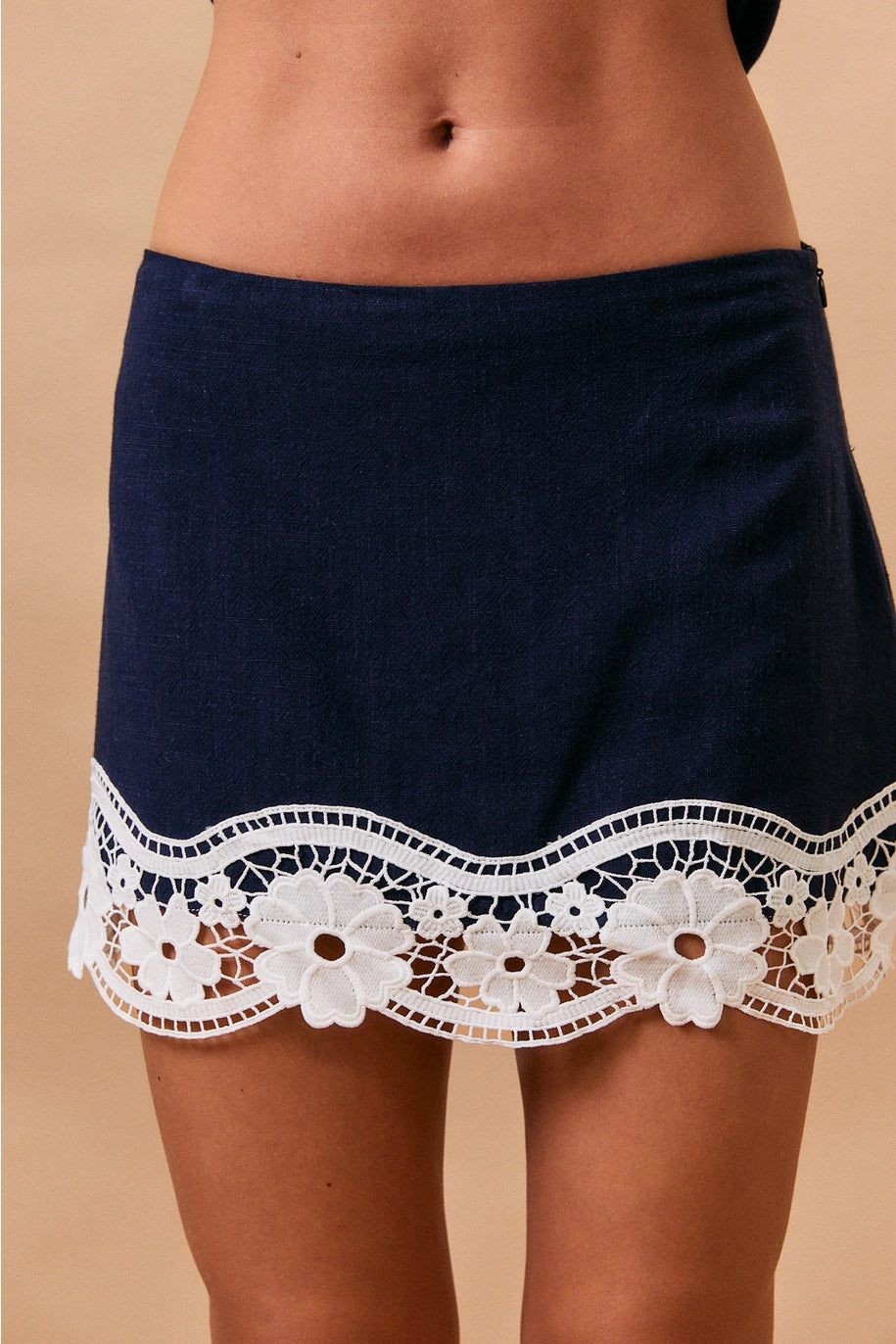 Navy blue shorts with white lace trim on a beige background