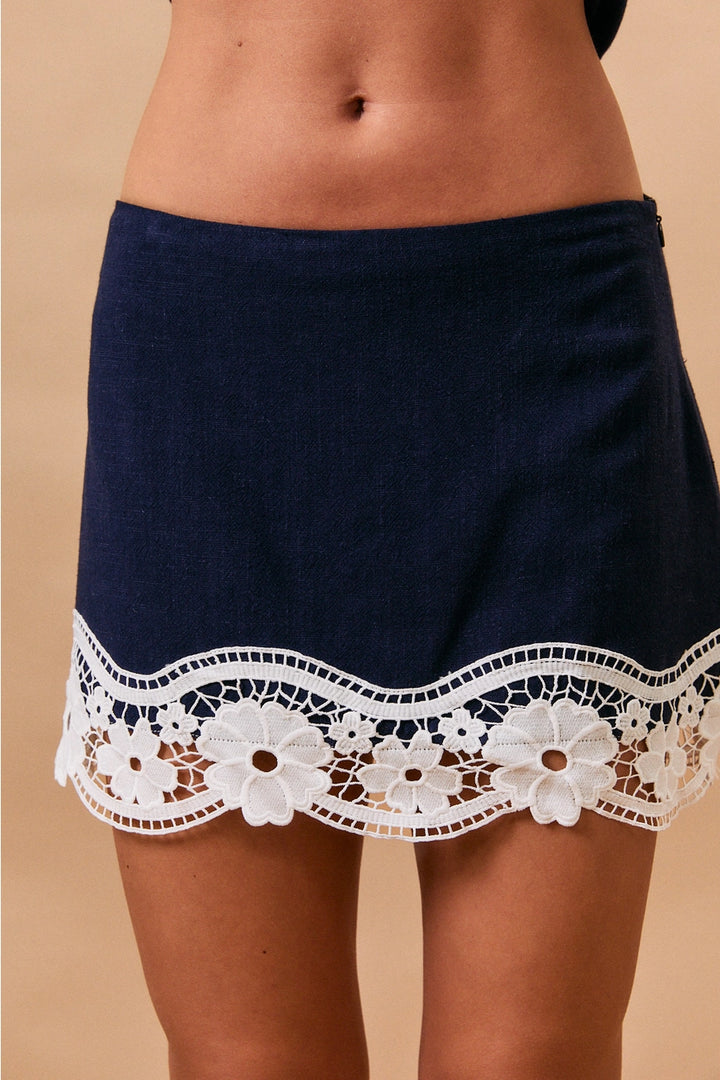 Navy blue shorts with white lace trim on a beige background