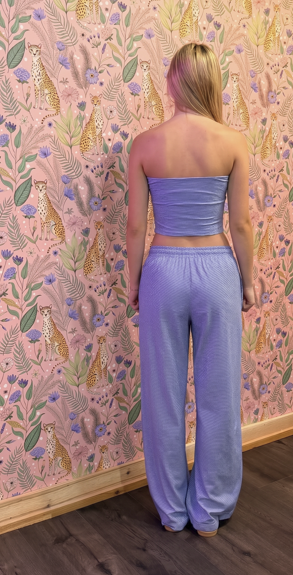 Person wearing a light blue outfit standing in front of a patterned wall.