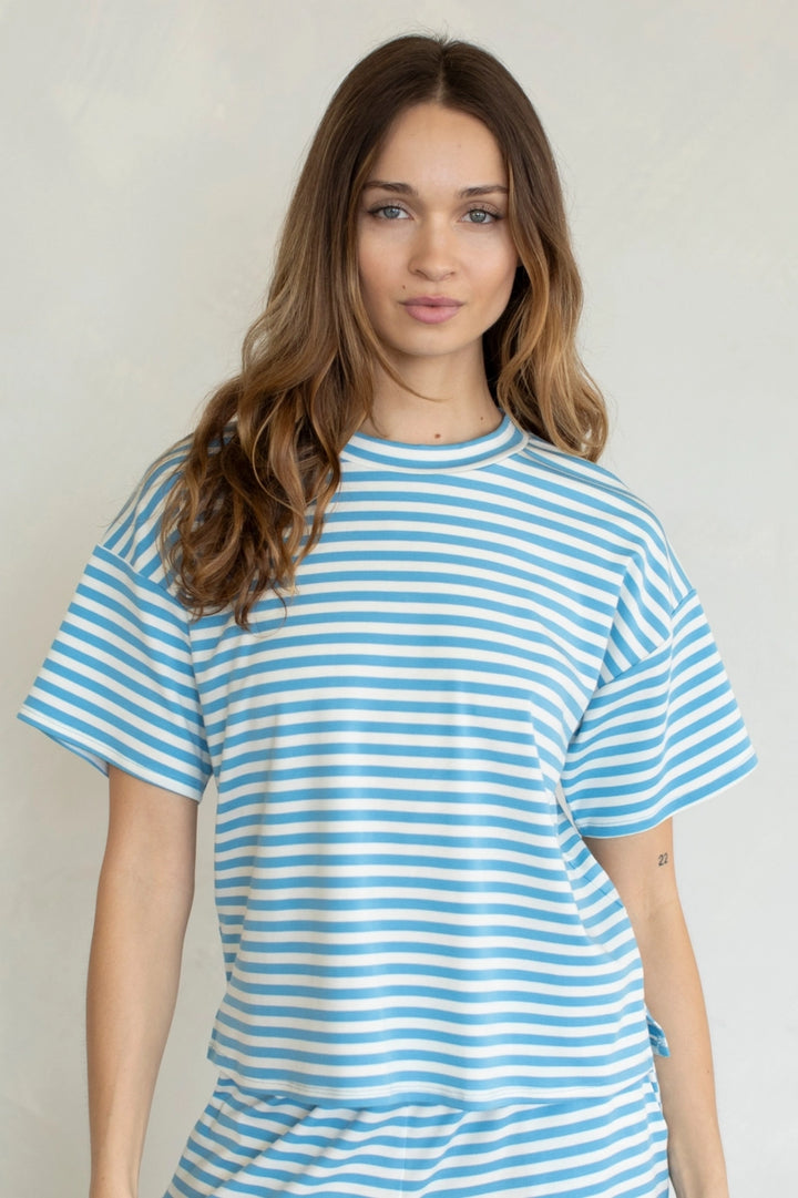 Woman wearing blue and white stripe tee on plain background