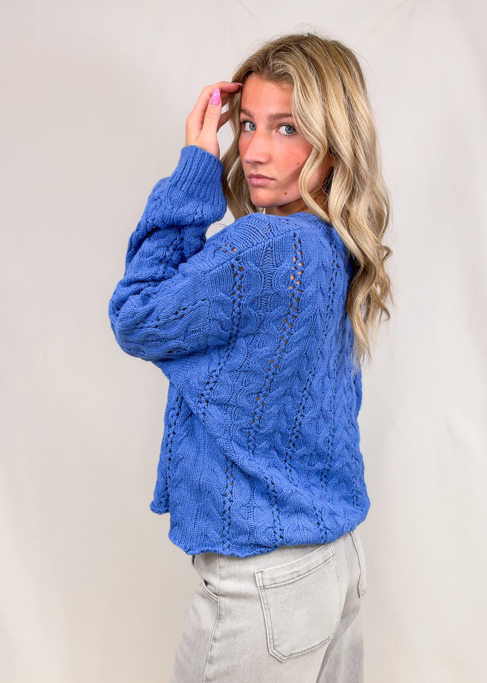 Woman wearing blue cable knit henley pullover on plain background