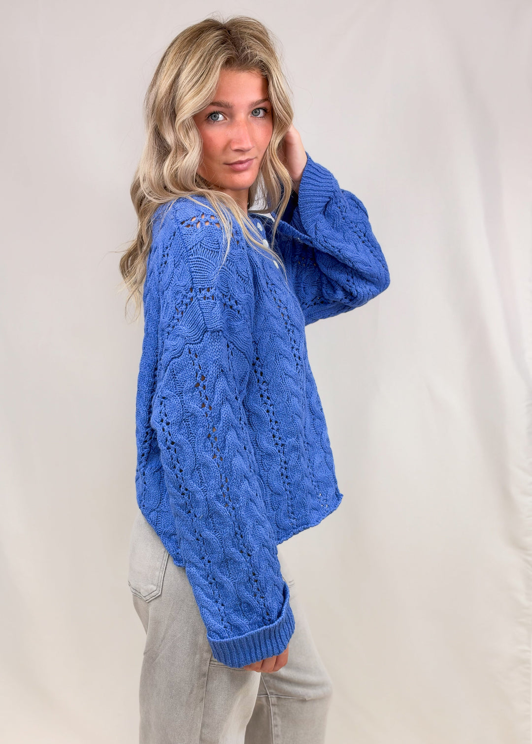 Woman wearing blue cable knit henley pullover on plain background