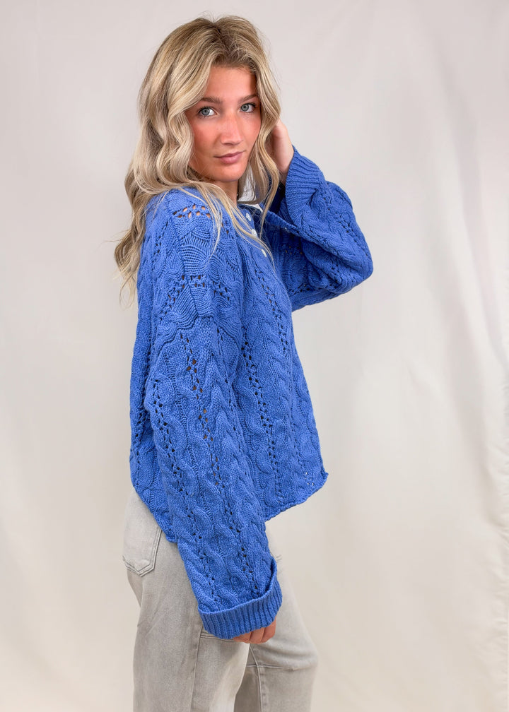 Woman wearing blue cable knit henley pullover on plain background