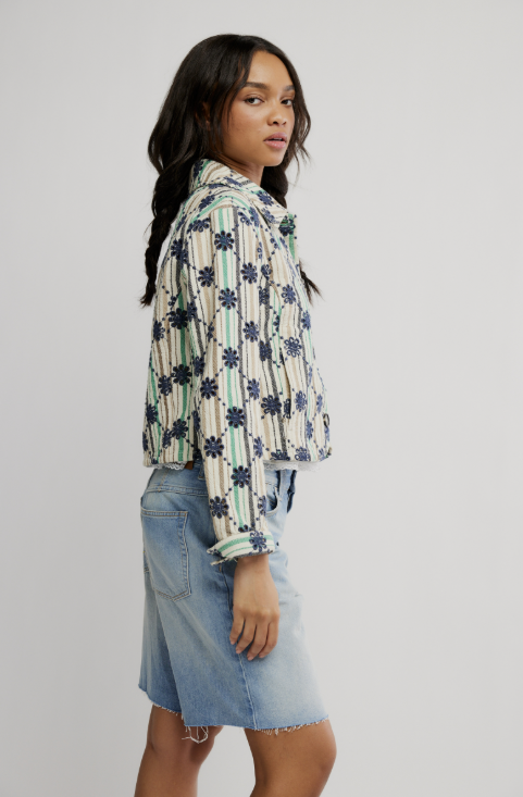 Woman wearing a patterned shirt and denim skirt on a plain background