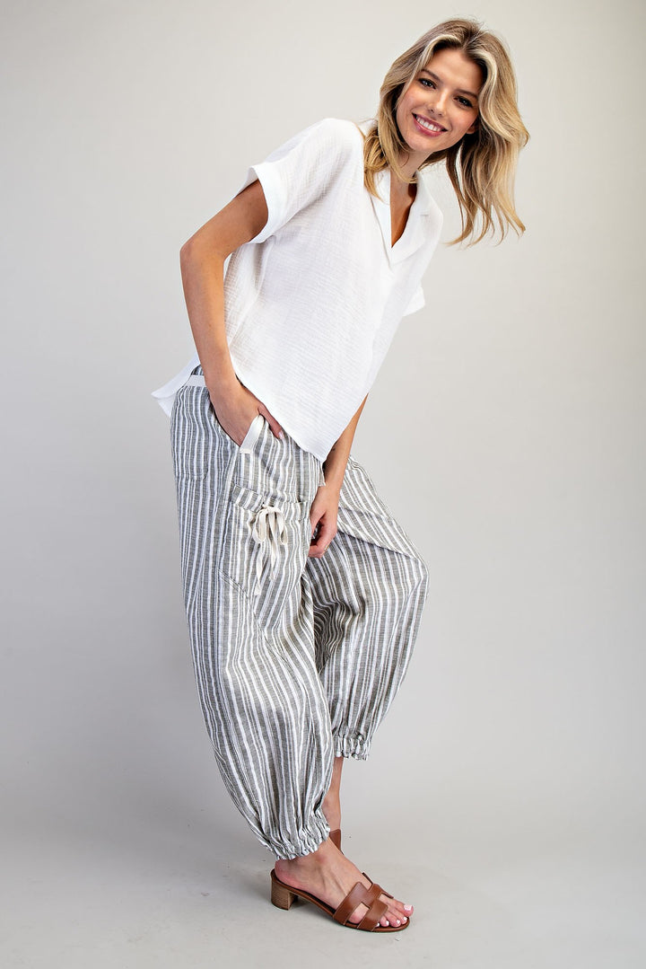Woman wearing a white top and striped pants on a plain background