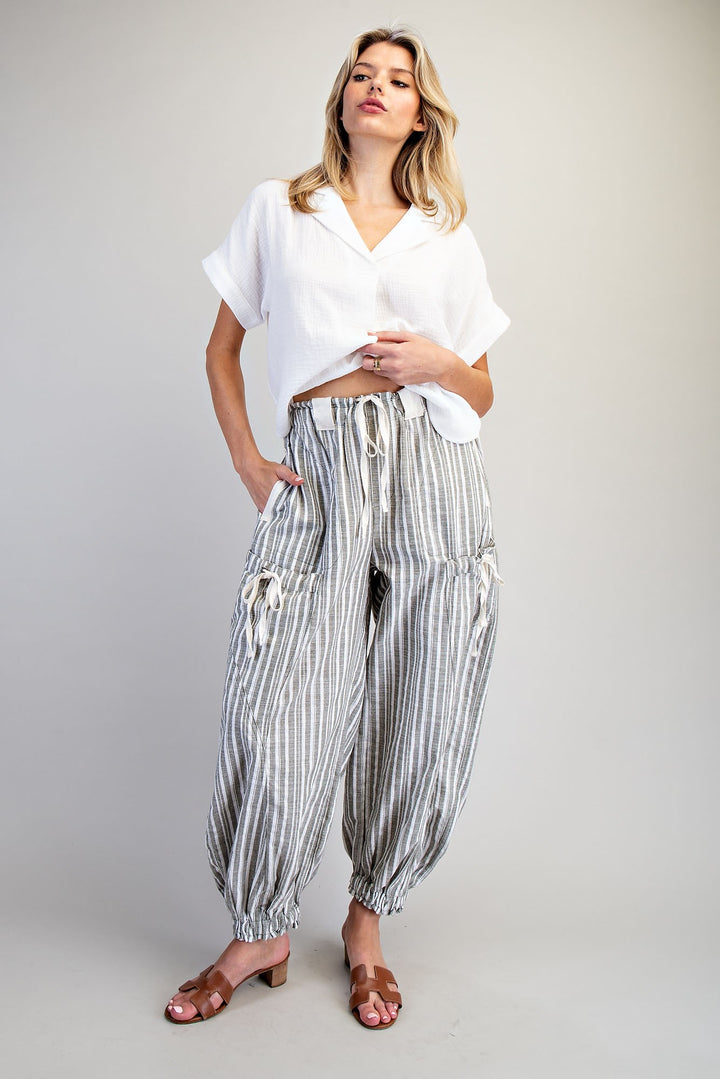 Woman wearing a white top and striped pants on a plain background