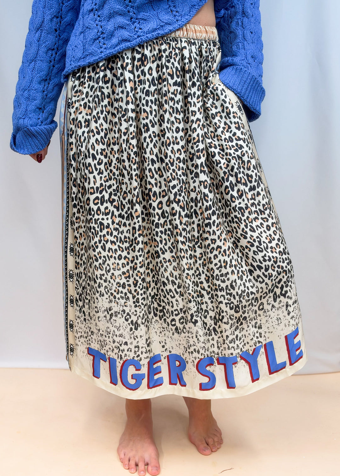 Woman shown from waist down wearing leopard satin skirt with &