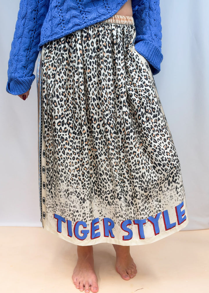Woman shown from waist down wearing leopard satin skirt with &