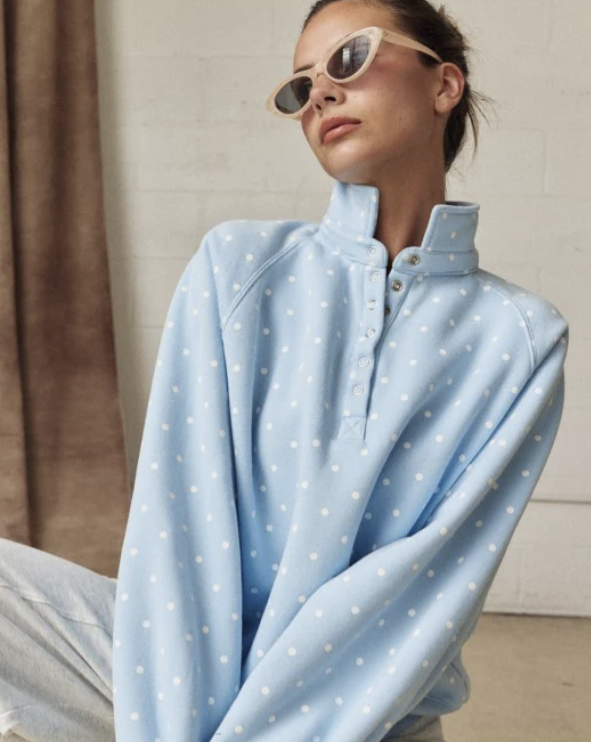 Woman wearing light blue polka dot sweatshirt on plain background