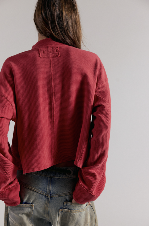 Woman shown from behind wearing red top and denim jeans on white background
