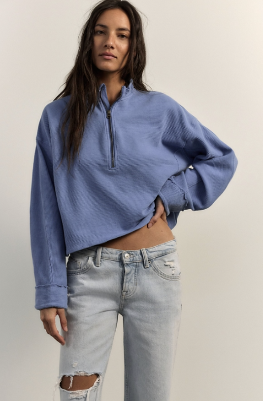 Woman wearing blue top and jeans on white background