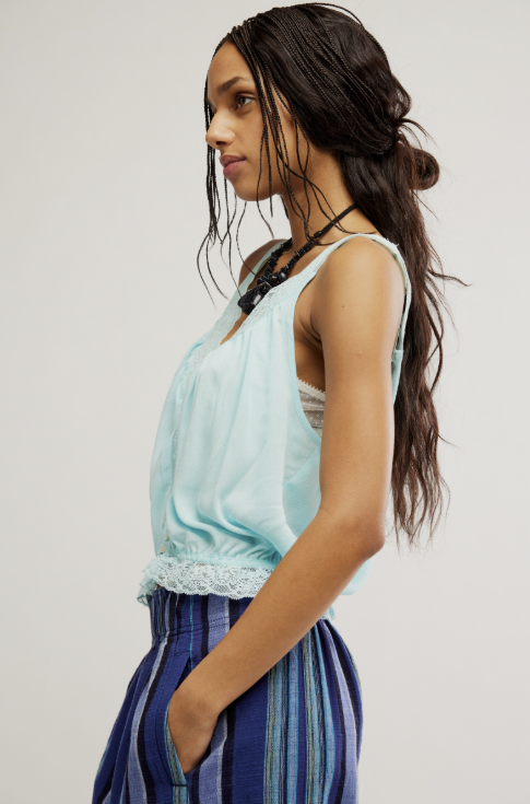 Woman wearing blue tank and blue pants on white background