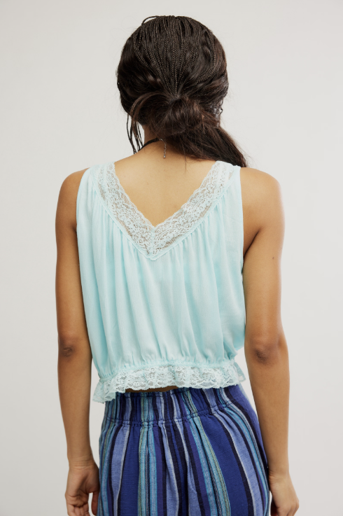 Back of woman wearing blue tank and blue pants on white background