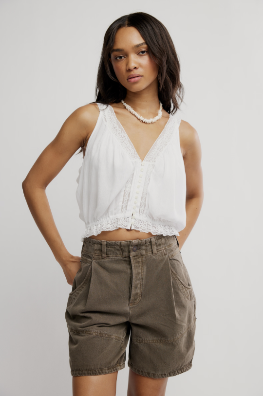Woman wearing white tank and brown shorts on white background