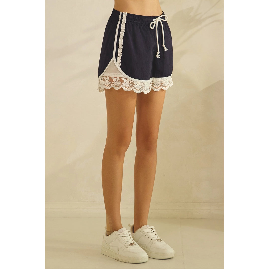 Navy shorts with white lace trim worn by a person on a beige background