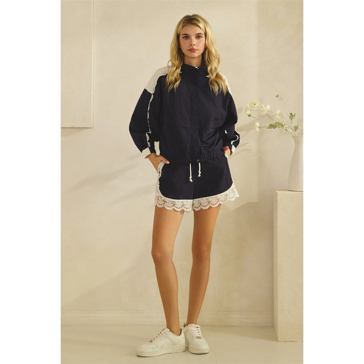 Woman wearing a navy blue outfit with white lace details in a minimalistic setting.