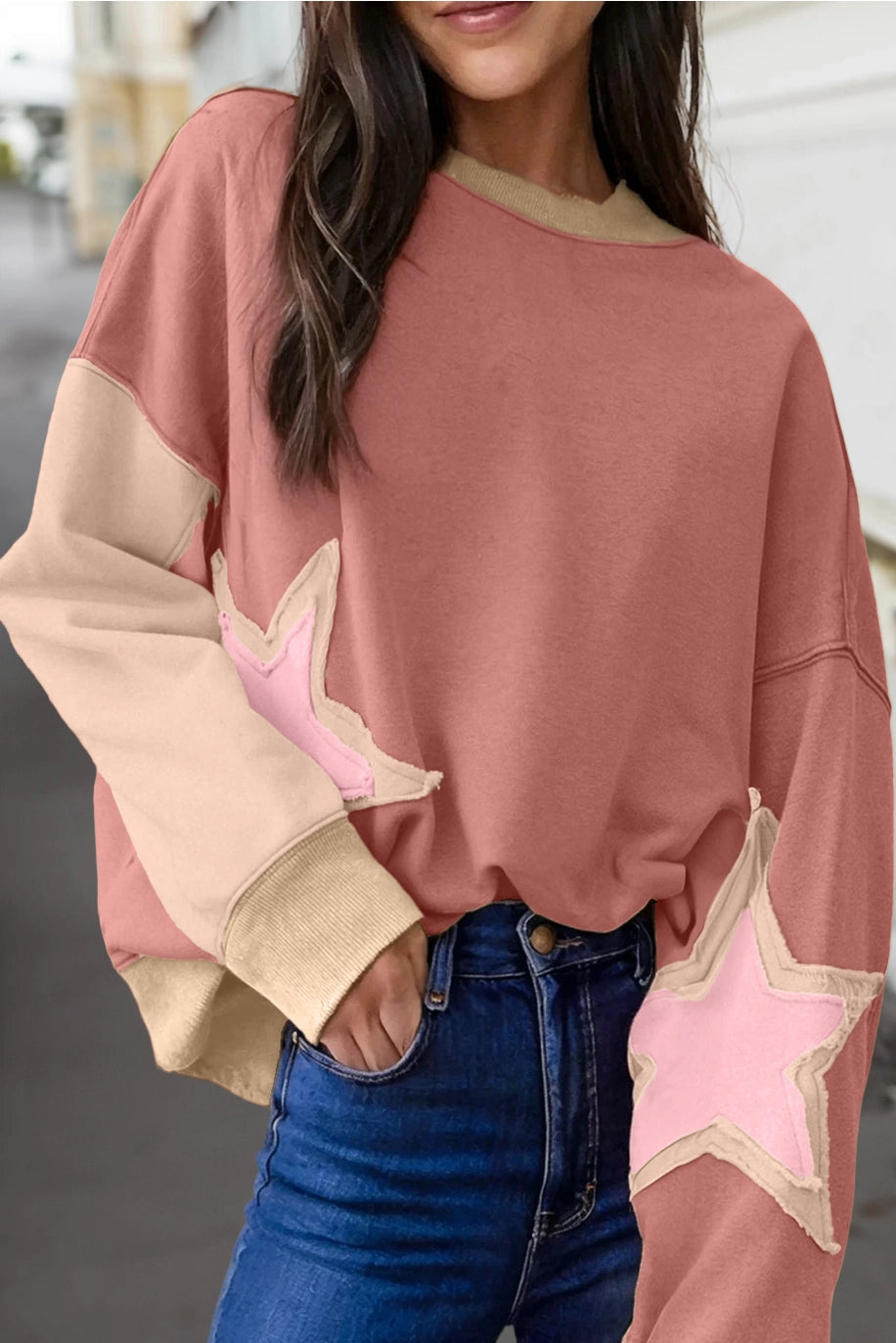Person wearing a pink and beige sweater with star details