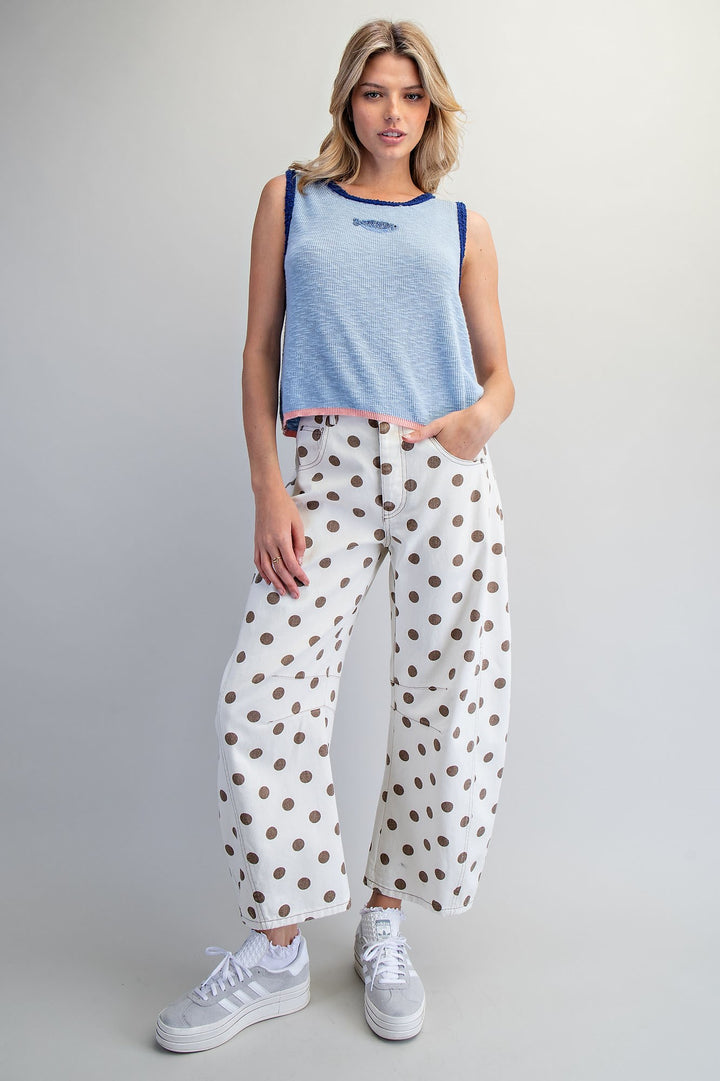 Woman wearing blue knit tank with beaded fish detail on plain background