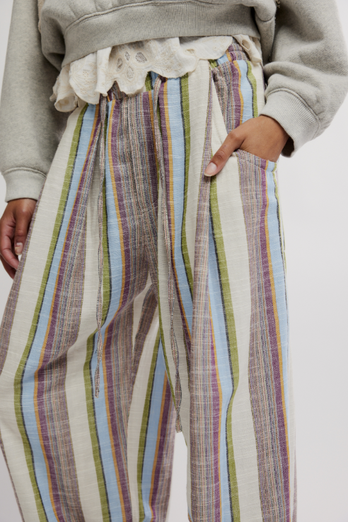 Person wearing colorful striped pants with a neutral background