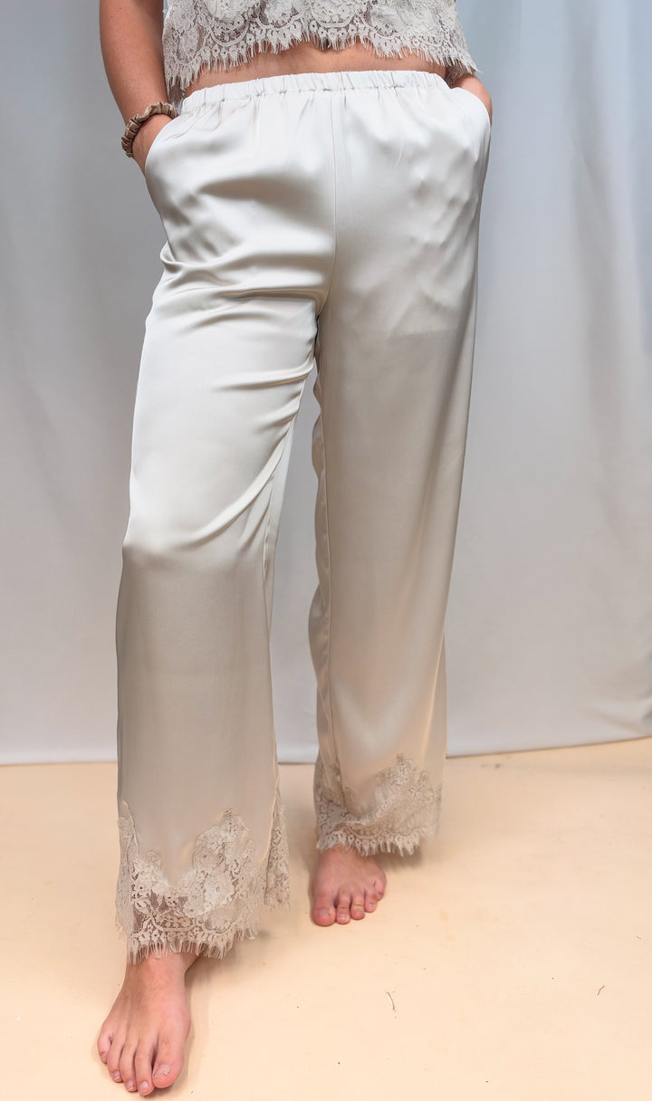 Woman shown from waist down wearing matching beige satin set with lace detail on plain background