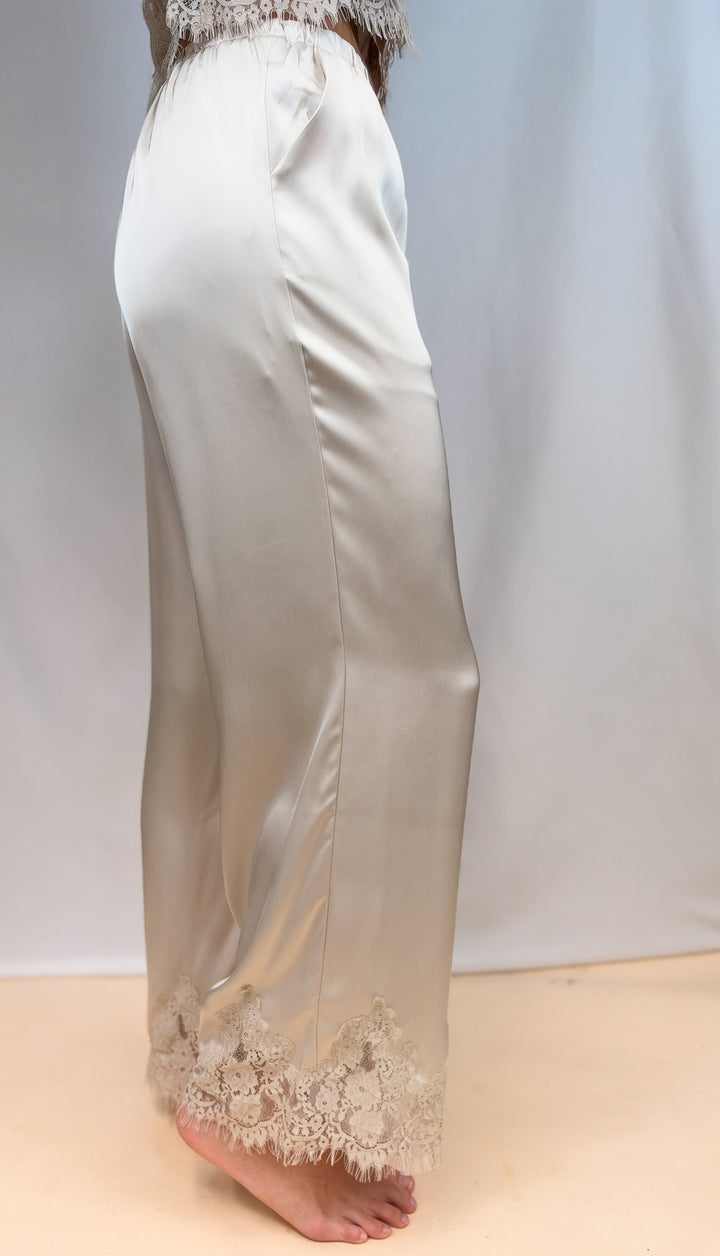 Woman shown from side view, waist down wearing matching beige satin set with lace detail on plain background