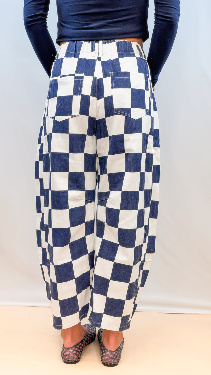 Woman shown from back wearing navy and white barrel pants and navy top on plain background