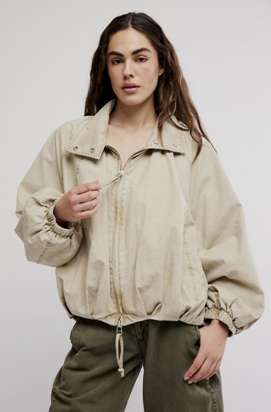 Woman wearing beige jacket and green pants on white background
