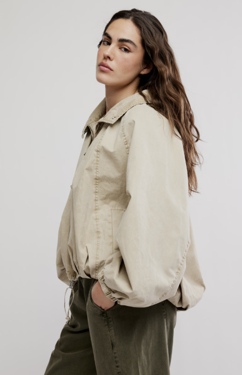 Woman wearing beige jacket and green pants on white background