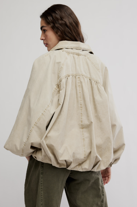 Woman wearing beige jacket and green pants on white background