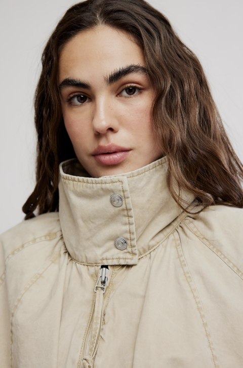 Woman wearing beige jacket on white background